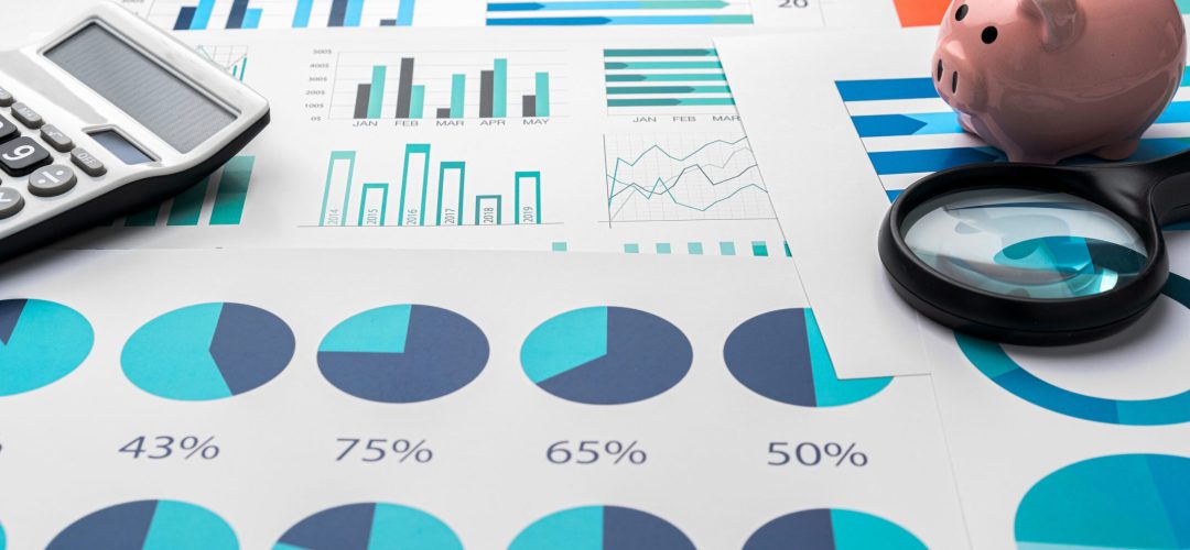 Business graphs and magnifying glass on table, close up
